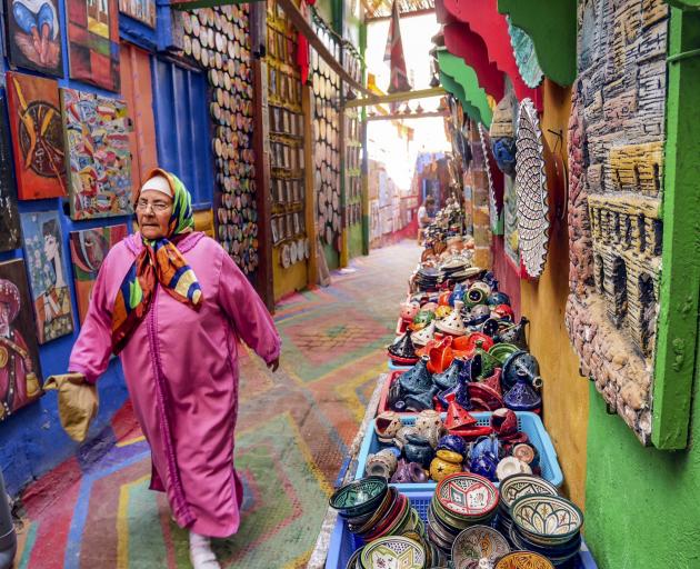 A woman walks down a brightly painted alley in Fez.