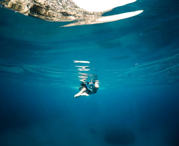 A young woman alone in the sea while doing snorkel. Photo: Getty Images