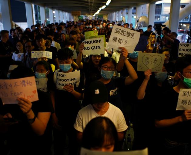 Protesters hold signs following a day of violence over the proposed extradition bill. Photo:...