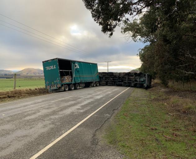 A Toll truck lies overturned on State Highway 8 near Tarras yesterday. The road was blocked for...