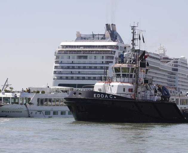The towering cruise ship MSC Opera has struck a dock and a tourist river boat on a busy canal in...