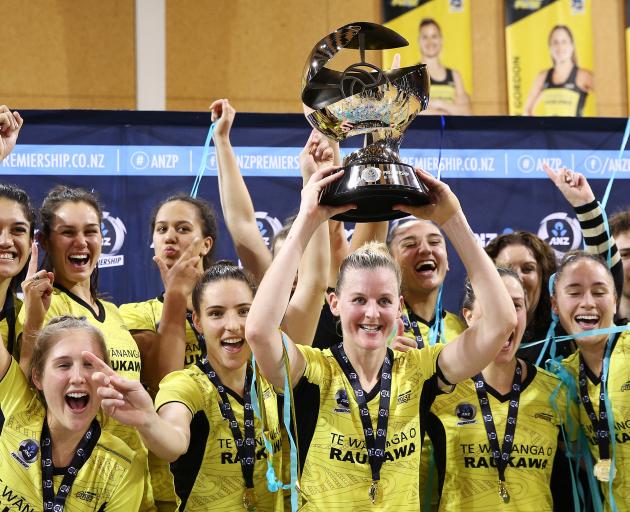 Pulse captain Katrina Rore holds the ANZ Premiership trophy aloft in front of her team-mates...