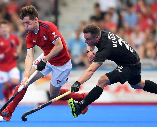 Shea McAleese, of the men's Black Sticks, is at full stretch trying to contain Great Britain's...