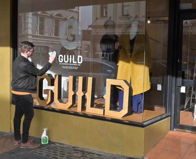 Dunedin Designed Inc chairman Craig Scott cleans the window of the new Guild store in Stuart St,...