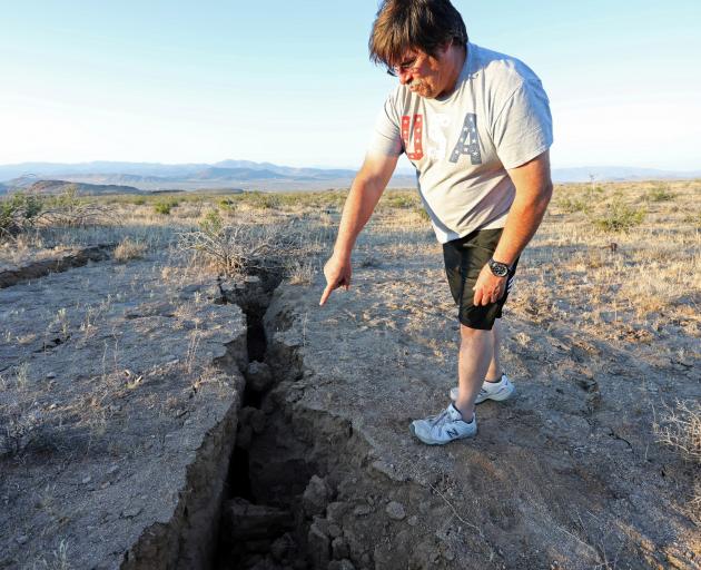 A man looks into a fissure that opened in the desert during a powerful earthquake that struck...