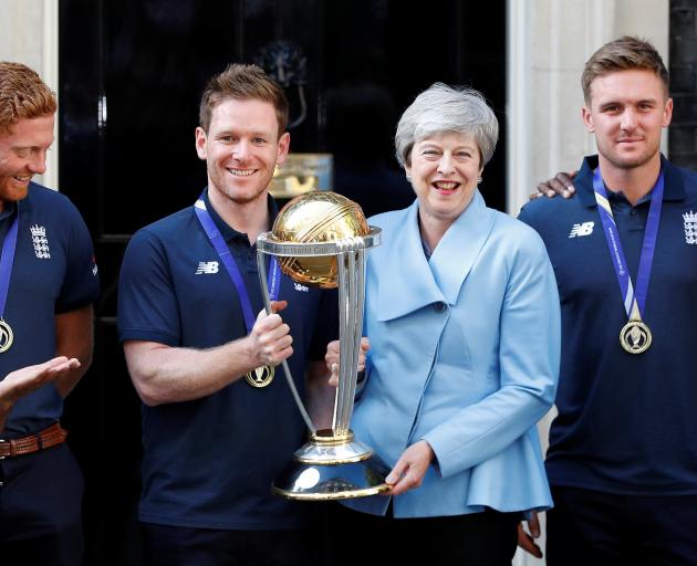 England captain Eoin Morgan and Britain's Prime Minister Theresa May hold the trophy as they pose...