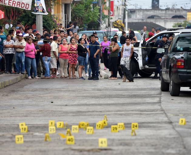 People stand near bullet casings on the ground at a crime scene after a shootout in the municipality Tuzamapan. Photo: Reuters