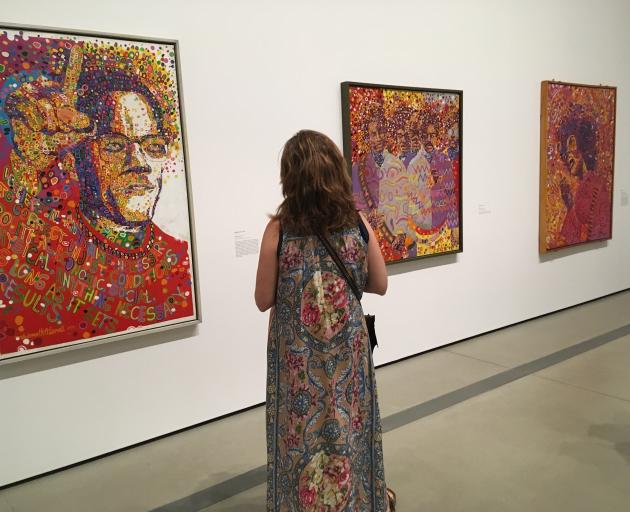 A woman examine's Wadsworth Jarrell's 'Black Prince', a portrait of Malcolm X, and other Jarrell...
