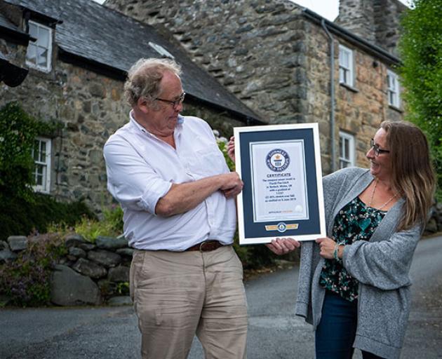 Harlech residents Gwyn Headley and Sarah Badham admire the certificate from the Guinness World Records officially recognising their street Ffordd Pen Llech as the world's steepest. Photo: Supplied