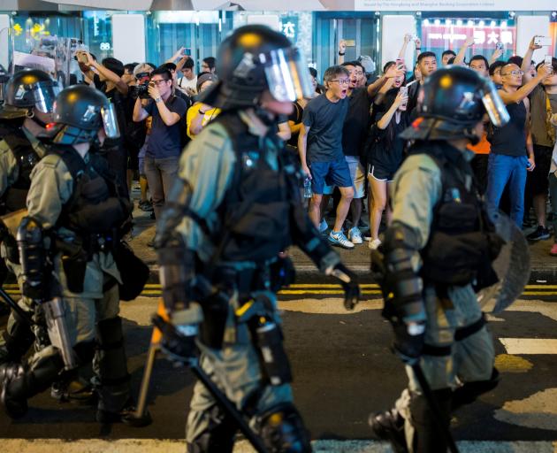 Locals shout at riot police as they chase anti-government protesters down in Mong Kok in Hong...