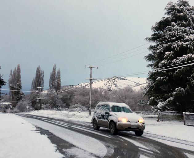 A car heads along a snowy Teviot Rd in Millers Flat on Monday morning. Photo: Supplied