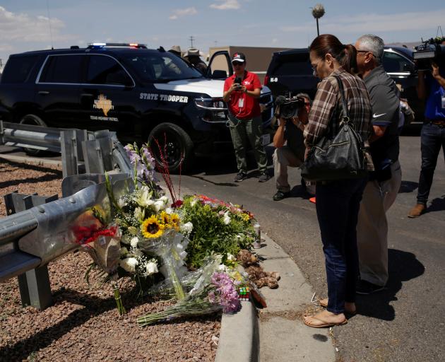 People look at flowers placed at the site of a mass shooting where 20 people lost their lives at a Walmart in El Paso. Photo: Reuters