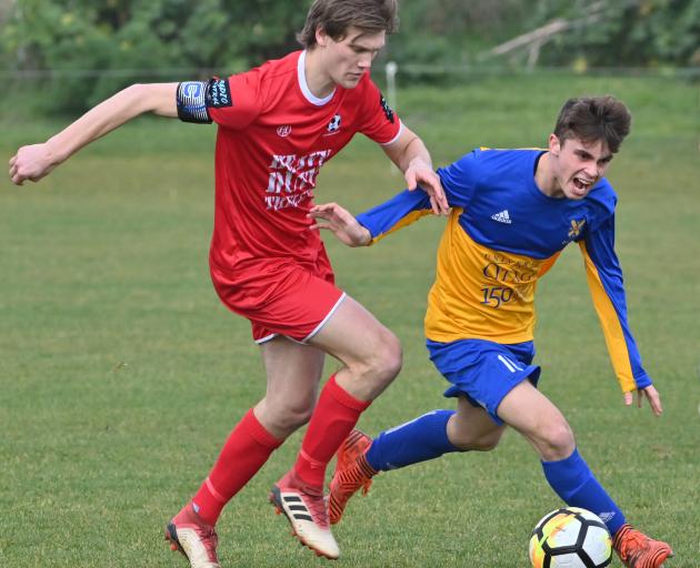 Caversham's Andrew Ridden (left) and Otago University's Edward Wilkinson compete for the ball...