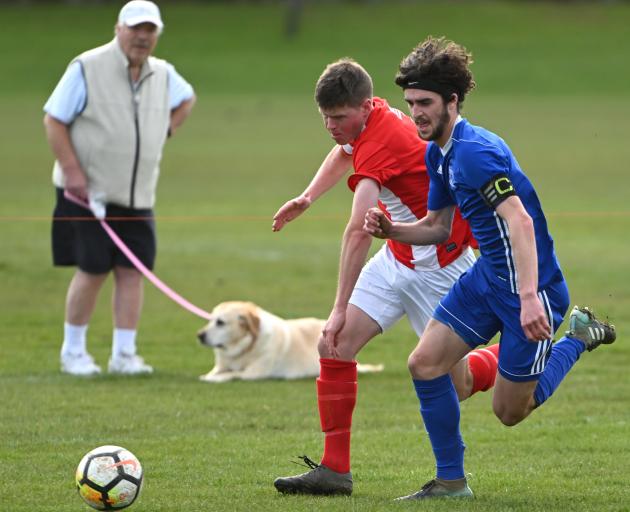 Mosgiel’s Rory Findlay (in blue)  and Nomads United’s Liam Thompson race for the ball during...