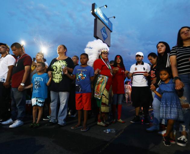 Children and adults gather outside the El Paso Walmart where a white supremacist gunman killed 22...