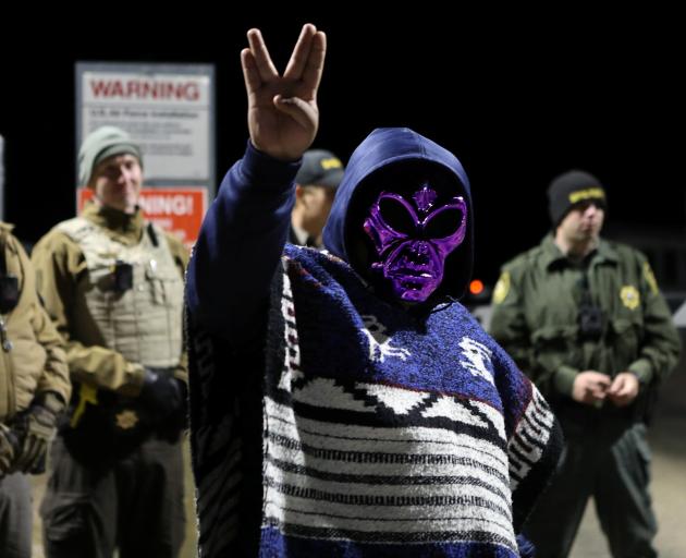 An attendee wears an alien mask at the gate of Area 51 as an influx of tourists responding to a...