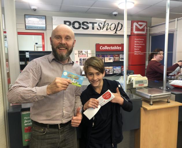 The new coupon book gets the thumbs-up from Brett Jones, owner/manager of the Amberley Post Shop, and Amberley School's head boy, Leo Bain. Photo: Supplied