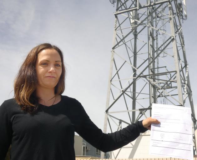 Alexandra woman Kelly Nyhon holds up a parliamentary petition she has launched opposing Spark's...