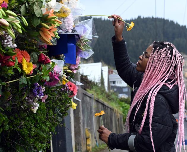 Tasha Gweshe (23), a student from a neighbouring flat, places flowers in the hedge at the flat in...
