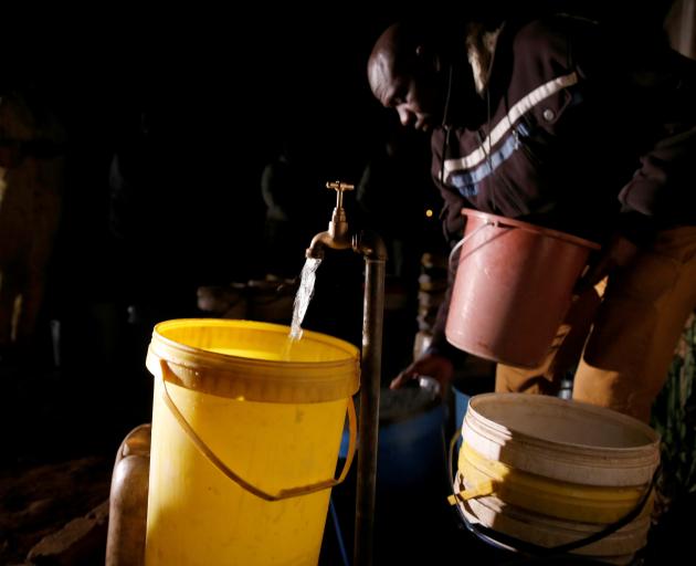 A resident collects water at night from an electric-powered borehole in Harare, as Zimbabwe faces...