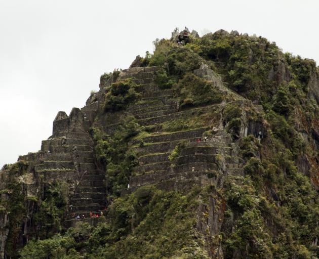 Some fit visitors to Machu Picchu climb steep steps to the top of Wayna Picchu, also known as...