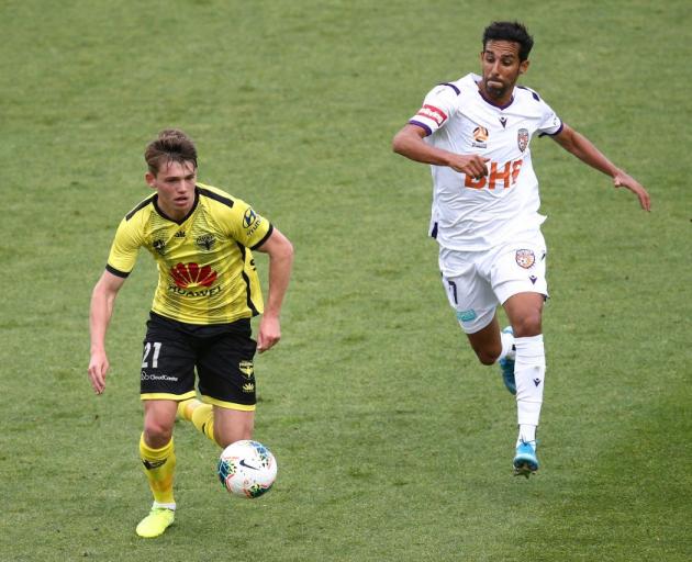 Callum McCowatt controls the ball for the Wellington Phoenix as the Perth Glory's Jaunde comes...