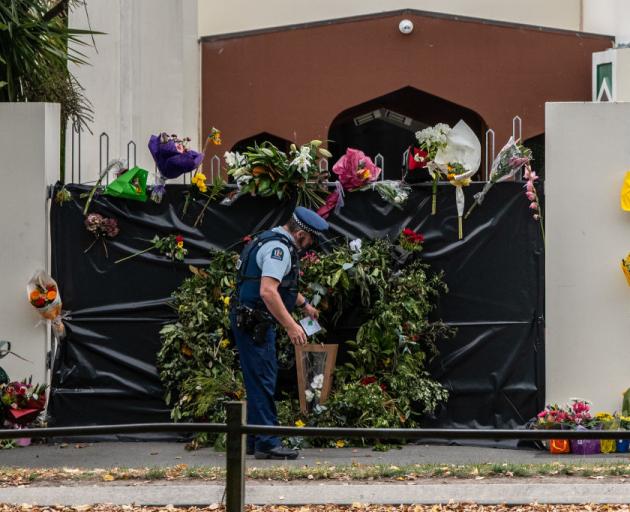A policeman places flowers on the gates of the Al Noor mosque. Photo: Getty/ Carl Court