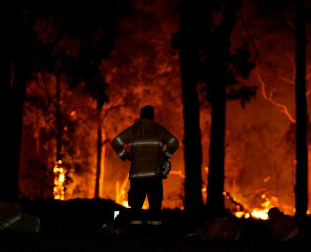 Fire crews take a moment’s rest as conditions ease on a fire surrounding a property in Colo Heights, New South Wales. Photo: Getty Images