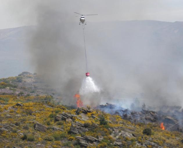 A helicopter discharges a monsoon bucket over the scrub fire. PHOTO: ADAM BURNS 