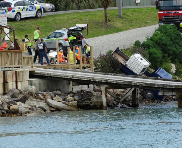 Emergency services tend to a man who was hit and injured by his own truck as it rolled towards the water in the seaside township of Moeraki yesterday. Photo: Daniel Birchfield