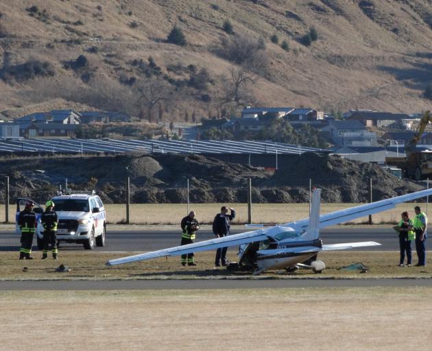 Police and Queenstown airport fire rescue staff examine the Cessna 177 damaged in an emergency...