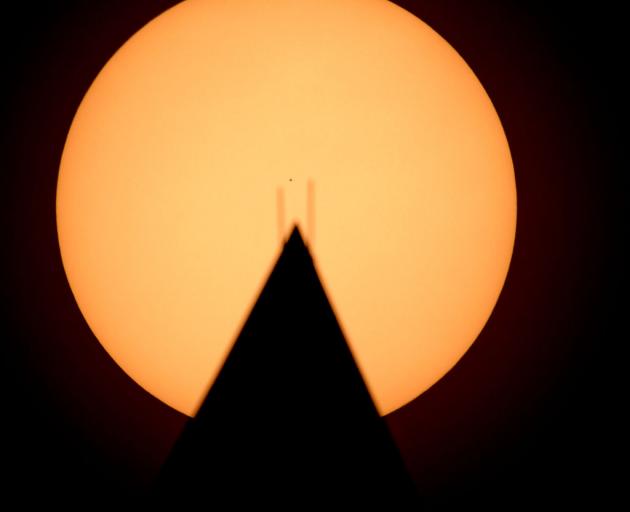 In this handout provided by NASA, the planet Mercury is seen in silhouette, center, as it transits across the face of the Sun, behind the Washington Monument. Photo: NASA via Getty Images