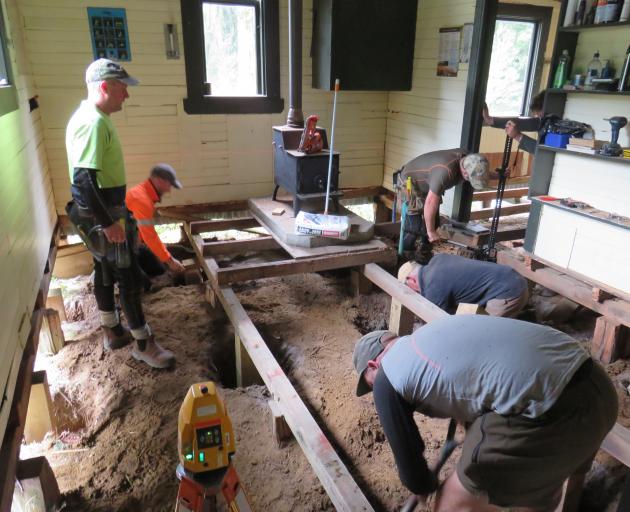 Members of the Wapiti Foundation remove flashings and lead-head nails during restoration work on...