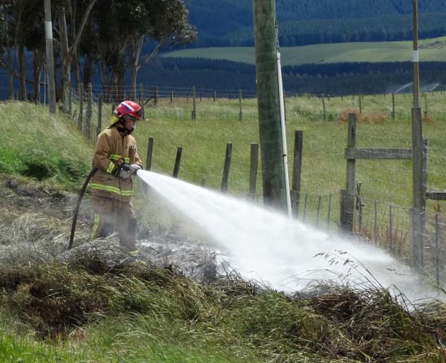 A firefighter tackles a grass fire in Island Stream Rd at Maheno yesterday. PHOTO: DANIEL BIRCHFIELD