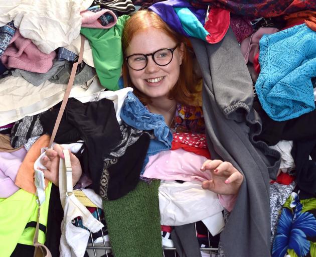 Among a large pile of clothes waiting to be sorted is Shop on Carroll retail assistant Sophia Borthwick. Photo: Peter McIntosh