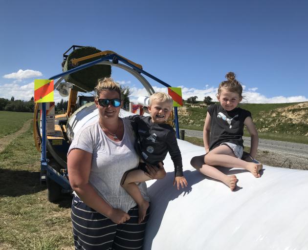Fine weather has contractors out in force making winter feed. Sarah Byrne with children Liam (4) and Nikita (6) take a break from the truck carting bales to the wrapper. Photo: Alice Scott