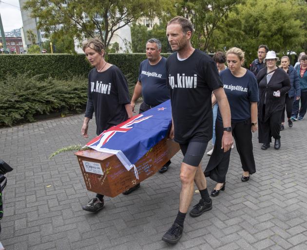 Camilla and Julian Cox and members of action group Patient Voice Aotearoa carry a coffin towards Parliament during their protest over Pharmac’s budget. Photo: The New Zealand Herald