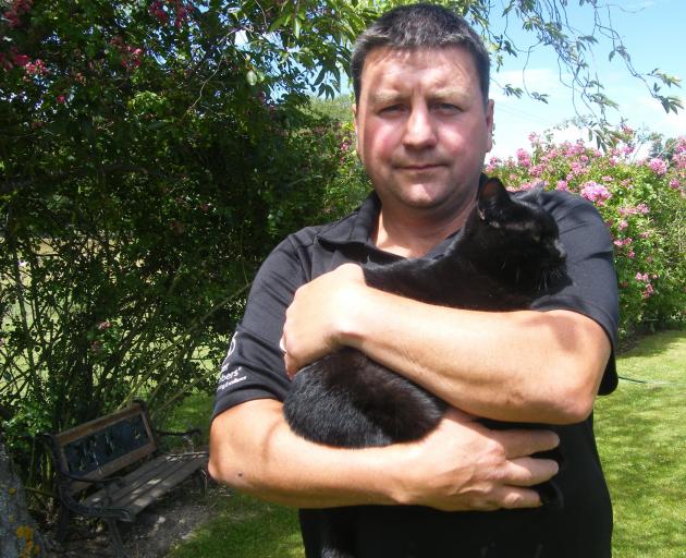 Alexandra man Harry Handford holds one of the family felines, Dogg. Photo: Adam Burns