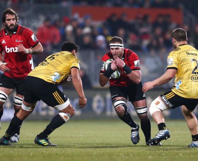 Kieran Read of the Crusaders runs at Isaia Walker-Leawere and Dane Coles of the Hurricanes...