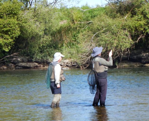 Chris Cowie on the SFFC course plays a trout on the Mataura while instructor Chris McDonald...