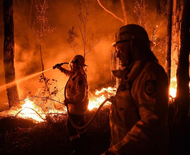 NSW firefighters work through the night to prevent a flare-up from crossing the Kings Highway in...