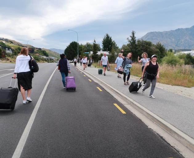 Travellers head towards and away from Queenstown Airport on Saturday morning on foot after a...