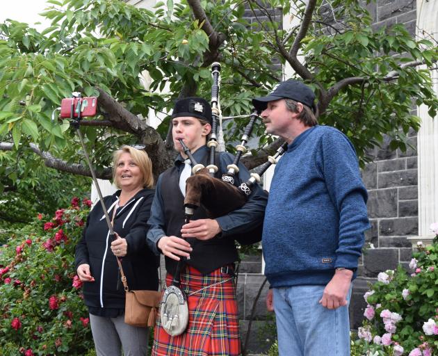Australian tourists Jody and Michael Thorne, of Sydney, take a selfie with bagpiper Wren Monks,...