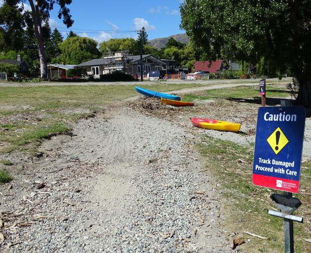 A sign warns walkers and cyclists about flood damage to a council track.