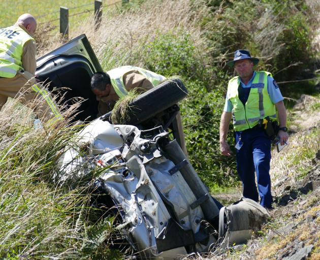 Police and fire personnel inspect a rolled vehicle on State Highway 1 near Lovells Flat, in South...