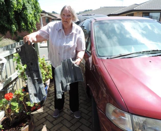 Flora Smith holds the remains of her destroyed right front mudguard while her car bears the scars...
