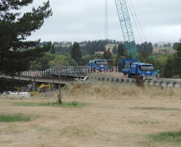 A truck travels over a Bailey bridge atop the Waiau River bridge, while earthquake repair work is carried out below. Photo: Robyn Bristow