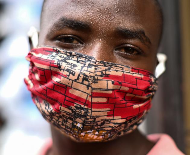 Pierre Mahiraguha, a vendor at the Kimironko market wears a handmade "kitenge" cloth mask in...