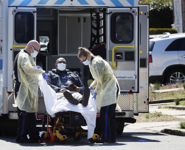 Ambulance staff lift a patient that was identified to have coronavirus disease (COVID-19) into an ambulance while wearing protective gear, as the outbreak of coronavirus disease (COVID-19) continues, in New York City. Photo: Reuters