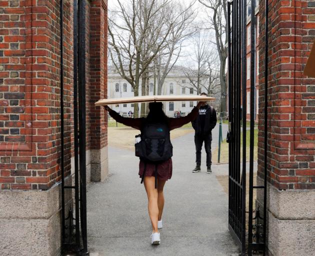 A student carries a box to her dormitory at Harvard University, after the university asked its...